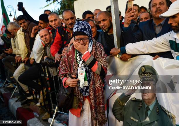 Woman mourns as she gathers with other people outside the "Palais du Peuple" during the funeral of Algeria's late military chief Lieutenant general...