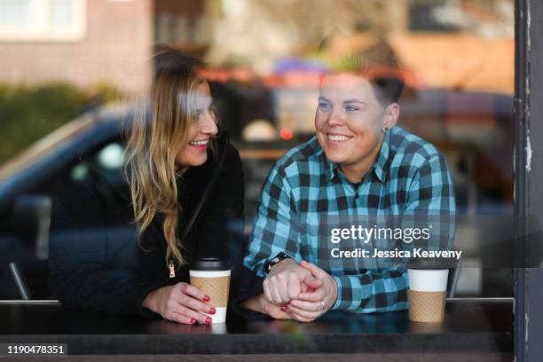 two women sitting in a cafe enjoying each others company. - coffee shop couple stock pictures, royalty-free photos & images