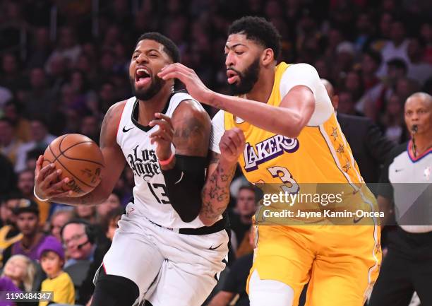 Anthony Davis of the Los Angeles Lakers guards Paul George of the Los Angeles Clippers as he drives to the basket in the first quarter of the game at...