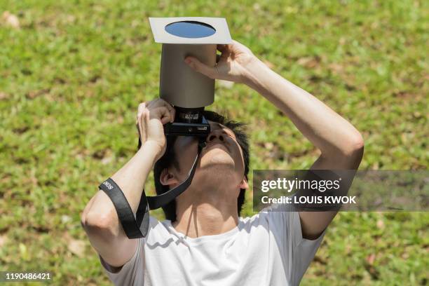 Man uses a homemade solar filter to photograph the moon as it moves in front of the sun in a rare "ring of fire" solar eclipse in Singapore on...