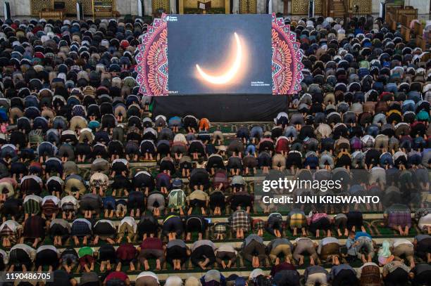People pray for the eclipse during a rare "ring of fire" solar eclipse in Surabaya on December 26, 2019.