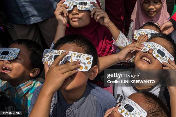 Children watch the moon move in front of the sun in a rare "ring of fire" solar eclipse in Surabaya on December 26, 2019.