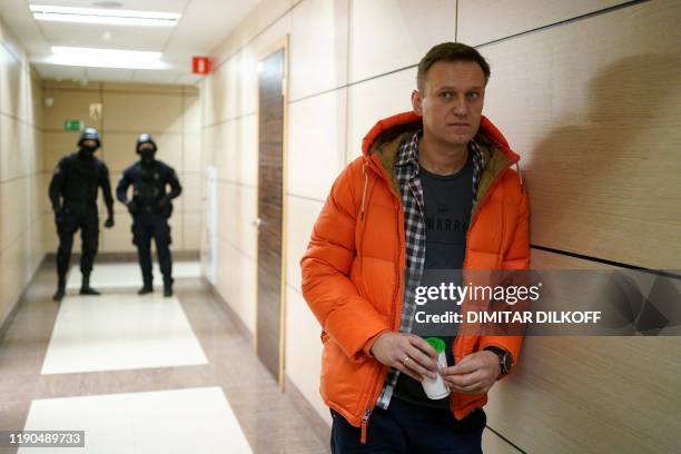 Russian opposition leader Alexei Navalny stands near law enforcement agents in a hallway of a business centre, which houses the office of his...