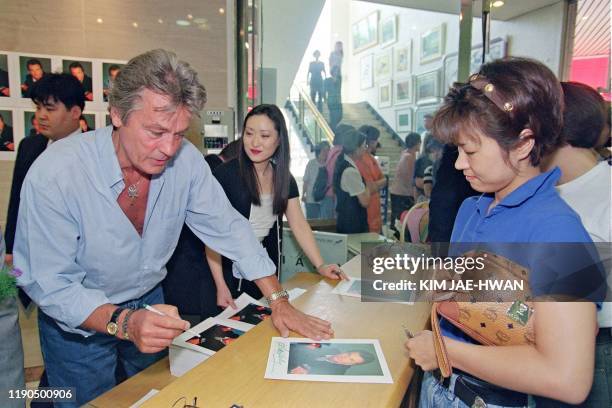 Photo d'archives prise le 26 juin 1996 de l'acteur français Alain Delon signant des autographes à des fans sud-coréens dans un grand magasin à Seoul...