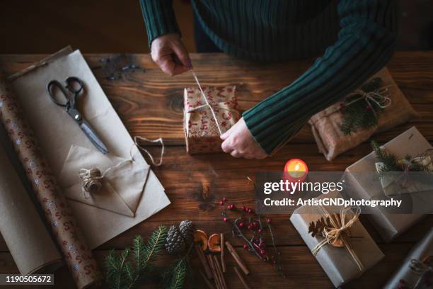 woman wrapping gifts on wooden table. - luxury lounges stock pictures, royalty-free photos & images