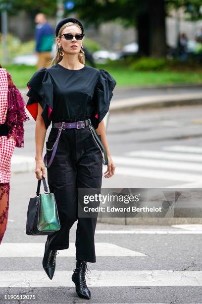 Guest wears a black velvet head band, sunglasses, earrings, a black top with a hot pink inner lining and ruffled sleeves, black crop pants, black...