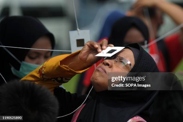 Woman uses a special lens to watch the phenomenon of the "ring of fire" solar eclipse. Ring solar eclipse was viewed in different regions in...