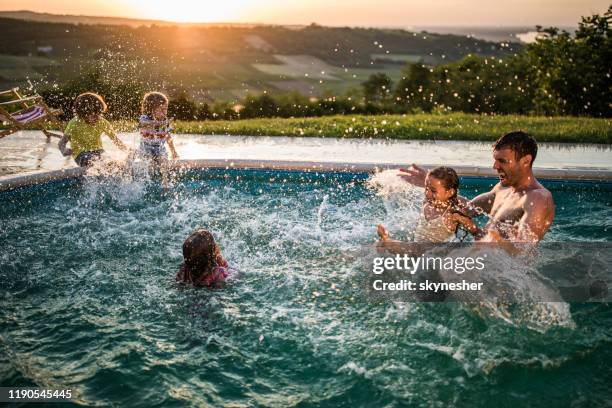 padre juguetón divirtiéndose con sus hijos en la piscina al atardecer. - backyard pool fotografías e imágenes de stock