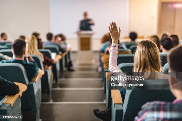 rear view of college student raising her hand in amphitheater. - answering stock pictures, royalty-free photos & images