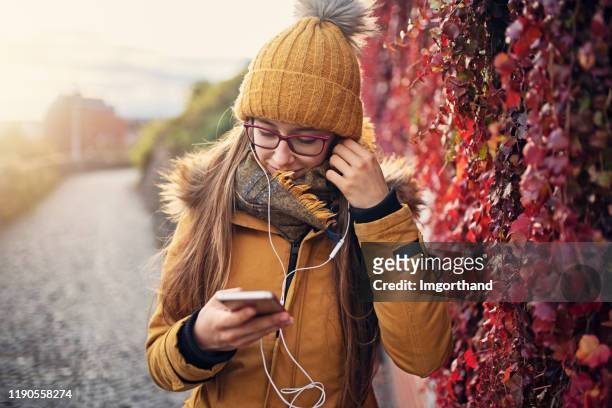 adolescente écoutant la musique le jour d'automne. - adult girl single park photos et images de collection