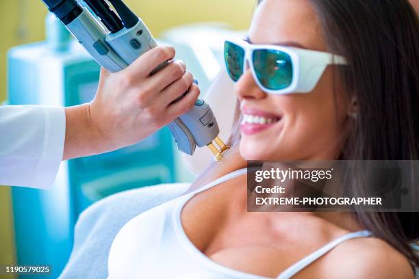 young woman getting a laser hair removal from her armpits in a cosmetic center - electrolysis stock pictures, royalty-free photos & images