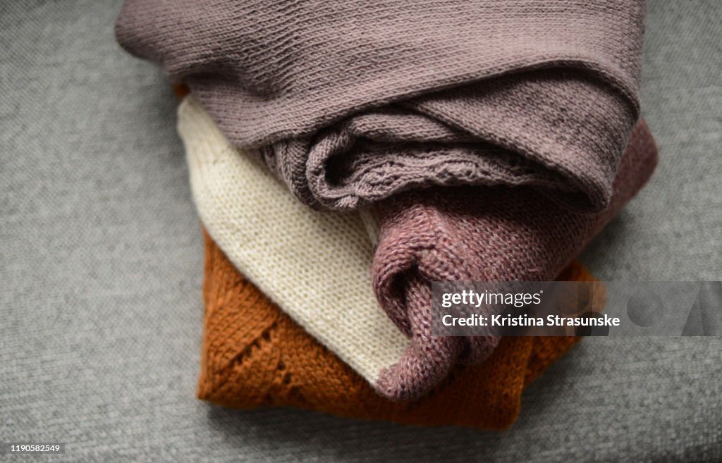 Three knitted sweater on a sofa