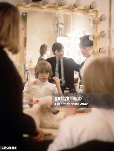 Brian Jones, of the Rolling Stones, backstage preparing for a performance, 1964. There is a poodle on dressing table.
