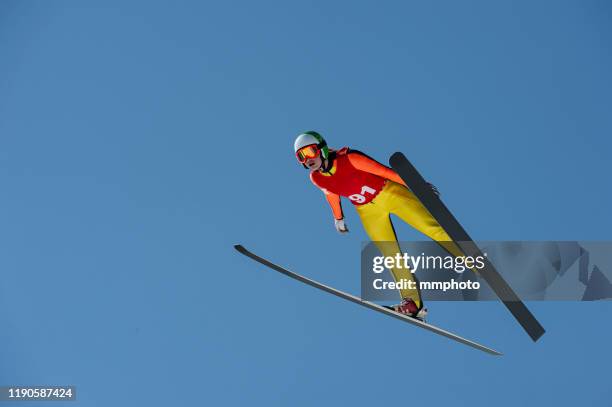 young women in ski jumping action against the blue sky - スキー　ジャンプ ストックフォトと画像