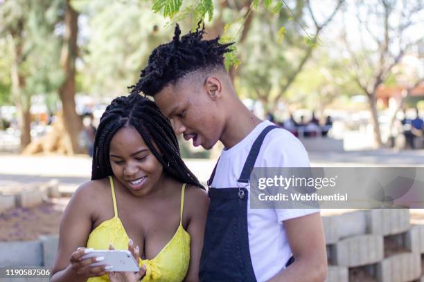 african couple looking at phone. - webfluential bildbanksfoton och bilder
