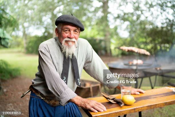 retrato de un gaucho senior preparando barbacoa - argentina traditional clothing fotografías e imágenes de stock