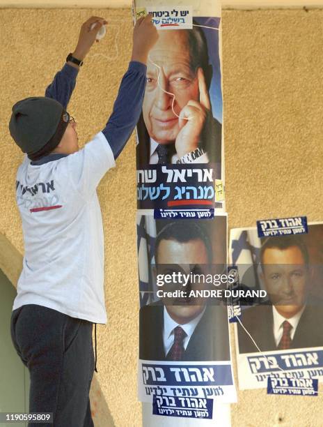 An Israeli boy hangs a poster of right-wing candidate for prime minister Ariel Sharon above one of caretaker Prime Minister Ehud Barak outside a...