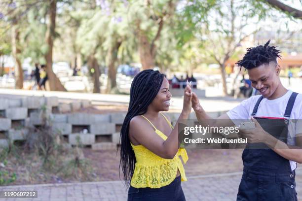 african couple looking at phone. - webfluential - fotografias e filmes do acervo