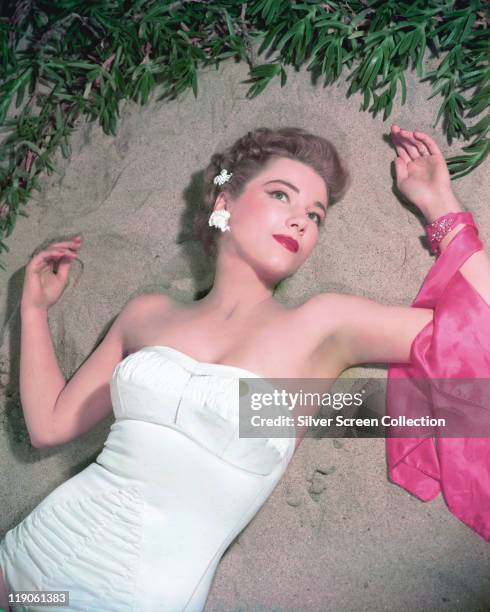 Anne Baxter , US actress, reclining on sand and wearing a white swimsuit, circa 1945.