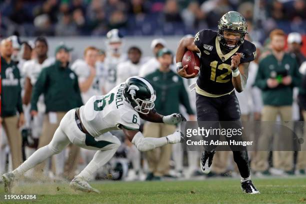 Quarterback Jamie Newman of the Wake Forest Demon Deacons rushes past safety David Dowell of the Michigan State Spartans during the first half of the...