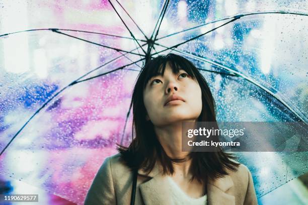 porträt der jungen asiaten frau unter regen in der nachtstadt - female with umbrella stock-fotos und bilder