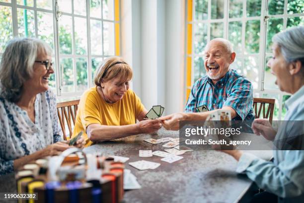 ancianos divirtiéndose jugando a las cartas en un asilo de ancianos - seniors fotografías e imágenes de stock