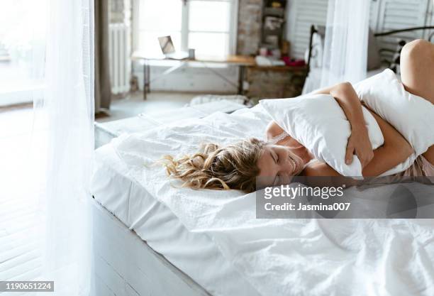 portrait of young woman enjoying time in bed - bedding stock pictures, royalty-free photos & images