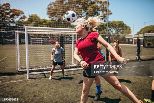 確定的女足球運動員在比賽中用頭玩 - shooting at goal 個照片及圖片檔