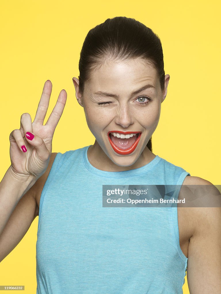 Young female winking and creating peace sign