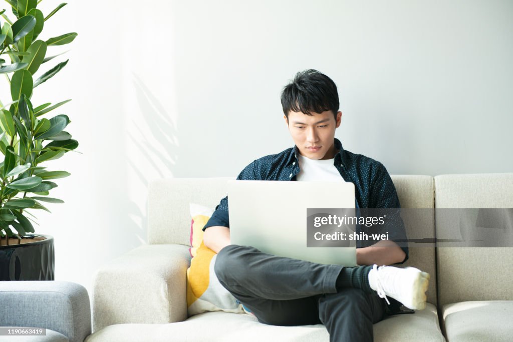 Japanese Man Using Computer Young Asian Man Using Computer In Living Room High-Res Stock Photo ...