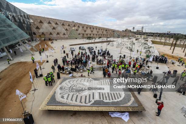 People gather around a depiction of the ancient Egyptian Pharaoh Tutankhamun's death mask made of 7260 cups of coffee, in front of the newly-built...