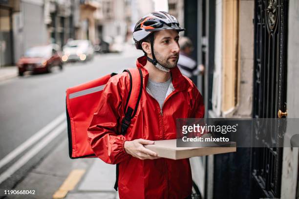man delivering food by bike in the city - pizza delivery stock pictures, royalty-free photos & images