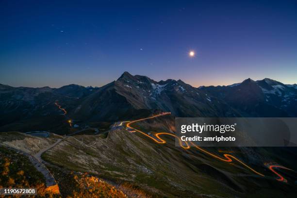 light trails on mountain pass road high up in european alps - european alps stock pictures, royalty-free photos & images