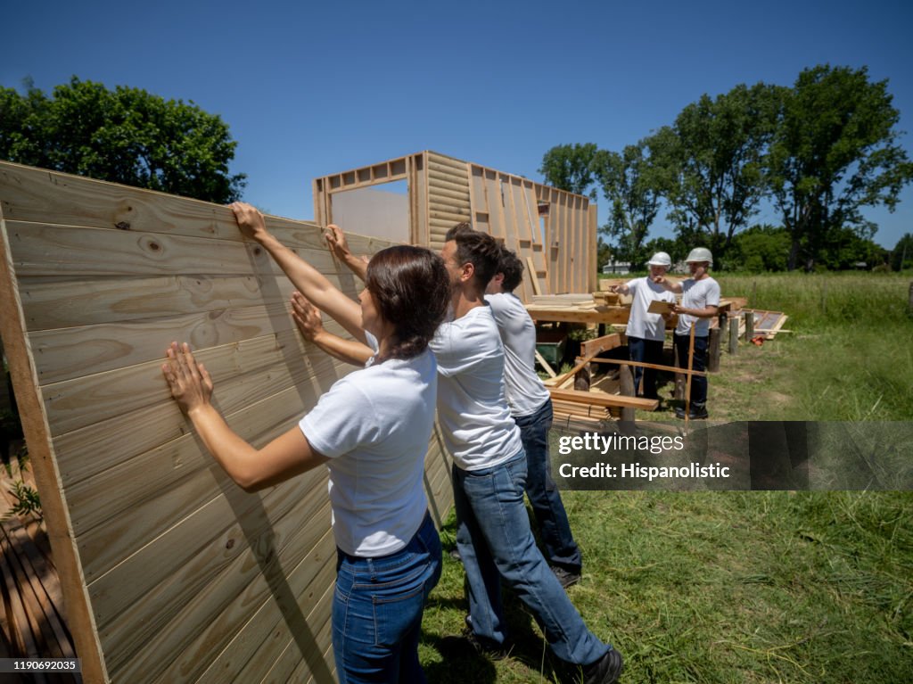 Latin american volunteers lifting up a wall at a charity construction project