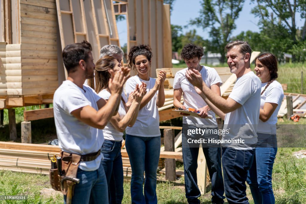 Group of latin american volunteers at a charity construction site in a meeting all clapping