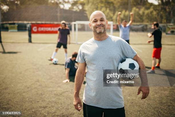 mid adult hispanic man met voetbal bal op de baan - bald man stockfoto's en -beelden