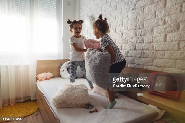 two adorable girls playing on a bed - sisters fighting stock pictures, royalty-free photos & images