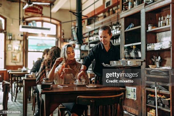 kellnerin serviert essen und trinken zu frau im café - kellner tablett stock-fotos und bilder