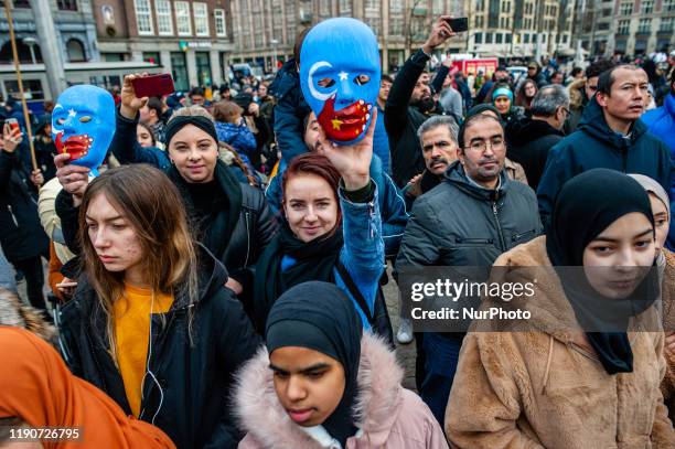 Woman is holding a mask with the Turkish and Chinese flag painted on it during the demonstration in solidarity with the Uyghurs, started in...