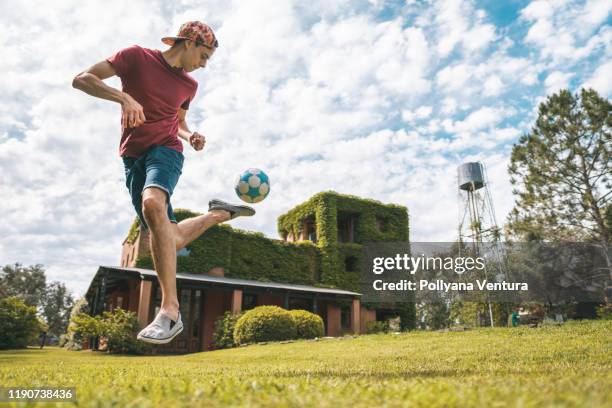 jeune homme jouant au football à la maison de campagne - exploit sportif photos et images de collection