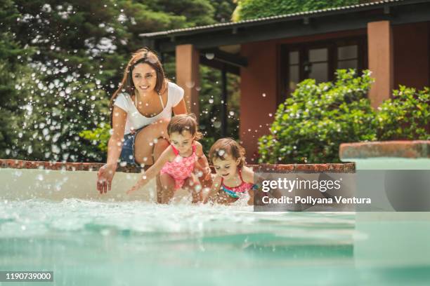 mom and her twin daughters playing in the pool - family backyard imagens e fotografias de stock