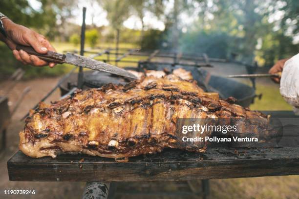 männer schneiden eine geräucherte rippe, grill im brennholz - smoked bbq ribs stock-fotos und bilder