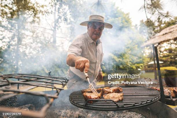 gaucho cutting a smoked rib, barbecue in the firewood - smoked bbq ribs stock pictures, royalty-free photos & images