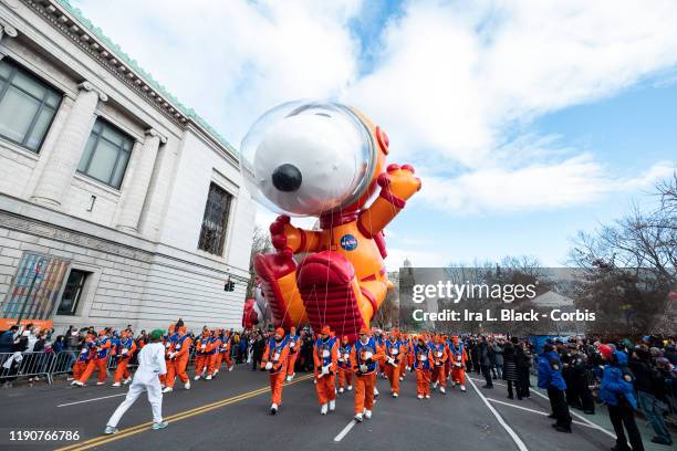 Balloon handlers try to keep Peanuts Astronaut Snoopy ballon safely flying despite the strong winds at the start of the 93rd Annual Macy's...