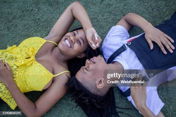 african couple lying on grass - webfluential - fotografias e filmes do acervo