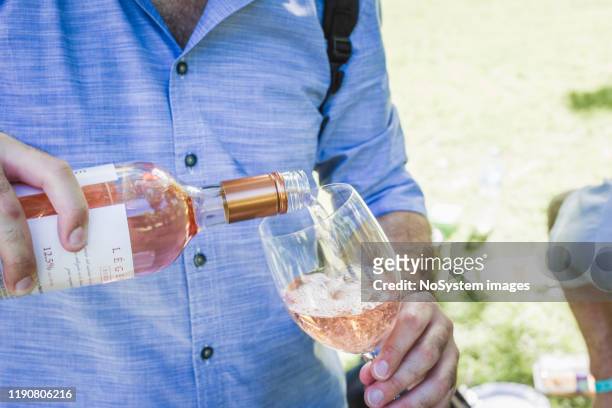 man is het gieten van rose wijn - single rose stockfoto's en -beelden