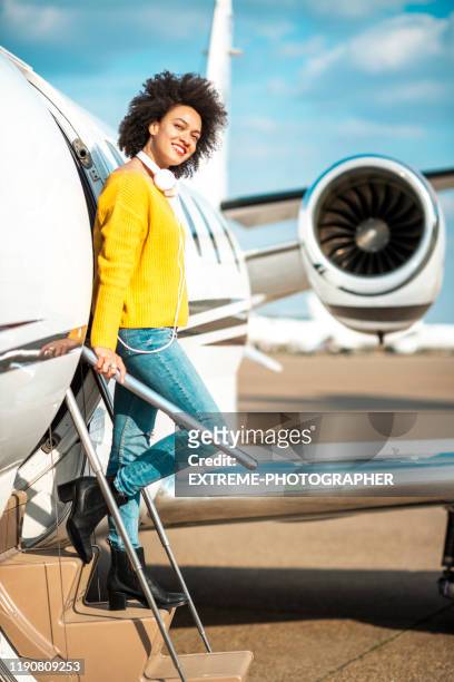 joven mujer bonita sonriendo mientras desembarca un avión privado - fuselage fotografías e imágenes de stock