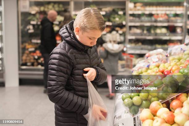 boy choosing apples in supermarket - teenager boy shopping stock-fotos und bilder
