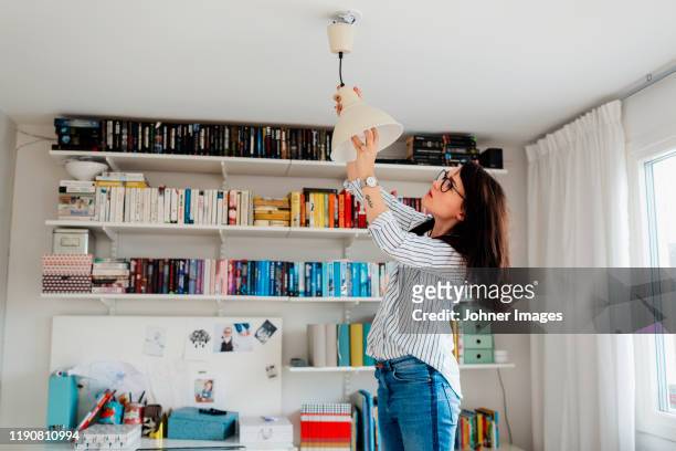 woman changing bulb in house - house shifting foto e immagini stock