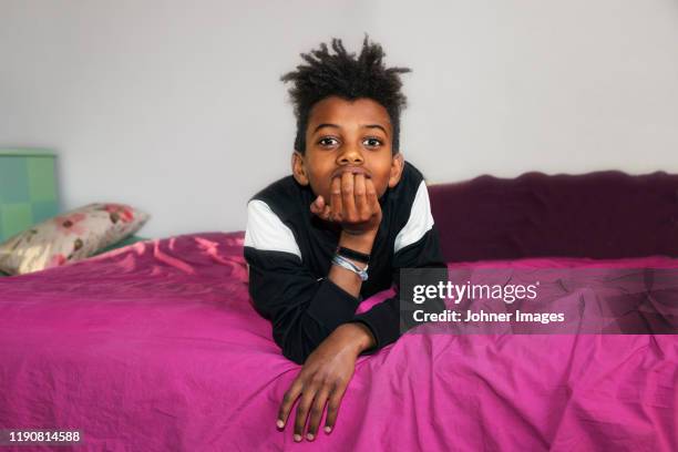 boy on bed looking at camera - boys bedroom stock pictures, royalty-free photos & images